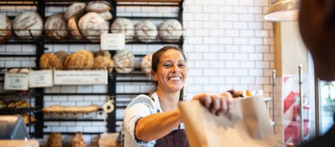 Photo de 2 personnes qui sont dans une boulangerie. La caissière a utilisé une caisse enregistreuse boulangerie